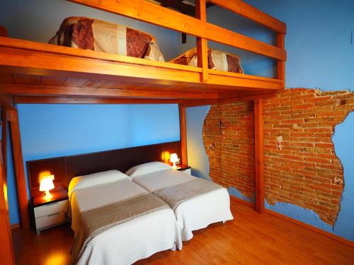 a bedroom with a bunk bed and a brick wall at Apartaments El Jaç in Montblanc