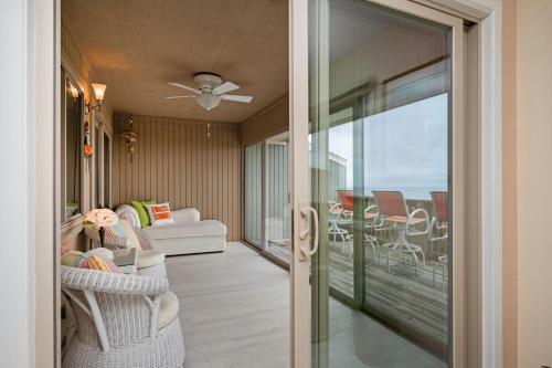 a room with a balcony with chairs and a living room at A Searious Sunset View by Oak Island Accommodations in Caswell Beach