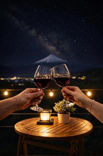 two people holding wine glasses on a table at night at Cabaña Con Impresionante Vista Volcan y Lago AYUN LAFQUEN in Villarrica