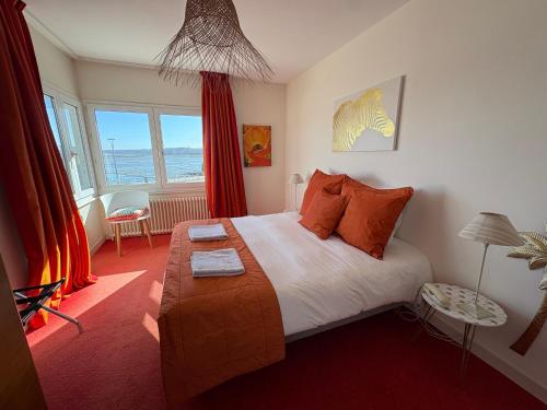 a bedroom with a large bed with orange pillows at La parenthèse du port in Perros-Guirec