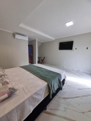 a bedroom with a large bed with a tv on the wall at Hotel Avalon in Benevides