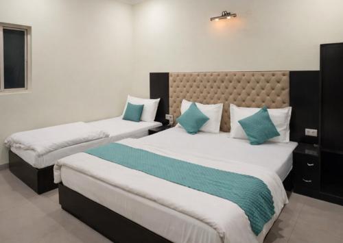 a bedroom with two beds with blue and white pillows at Hotel Grand Inn in Haridwār