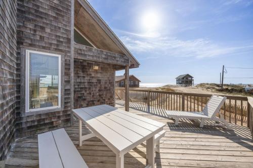 a wooden deck with a bench and a chair at 7026 - Southwind in Rodanthe