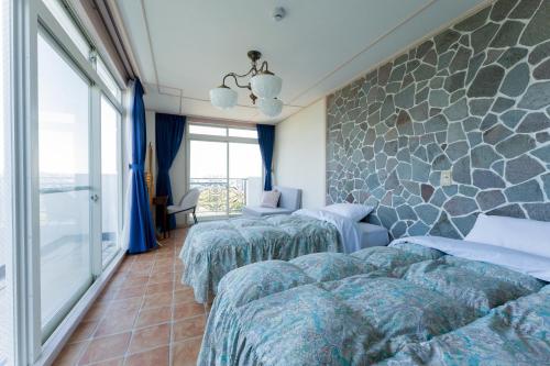 a hotel room with three beds and a stone wall at 全室オーシャンビューの宿 ルーチェ須崎 in Shimoda