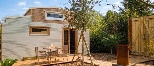 a tiny house with a table and chairs on a deck at La tiny house perdue in Saint-Blimont