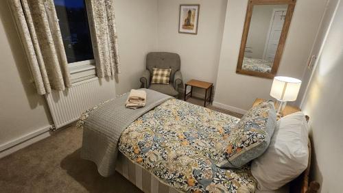 a bedroom with a bed and a chair and a window at Spacious 2 Bedroom Flat in Coatbridge in Coatbridge