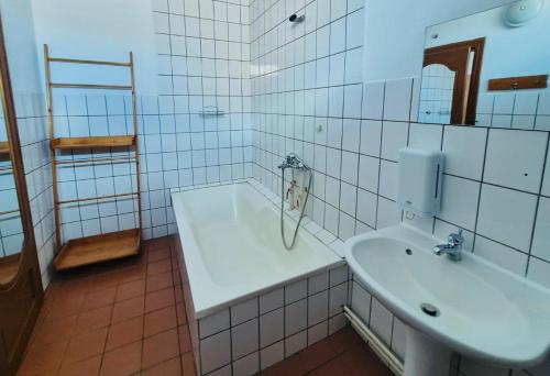 a white tiled bathroom with a sink and a mirror at La Răscruce in Gărâna