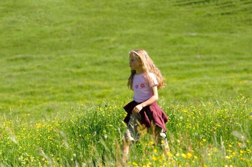 a little girl sitting in a field of grass at Hotel Sonnblick in Wald am Arlberg
