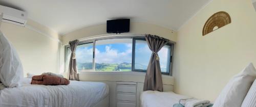 a bedroom with two beds and a window with a television at Ilhéu à Vista in Água de Alto
