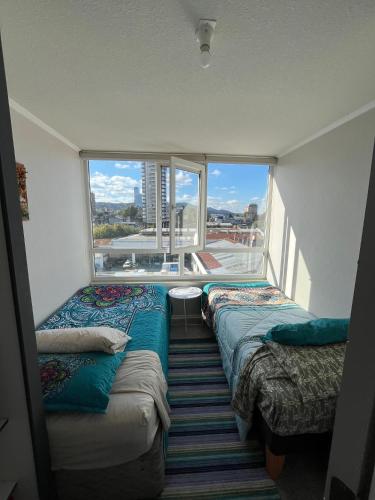 two beds in a room with a large window at Departamento 610 in Temuco