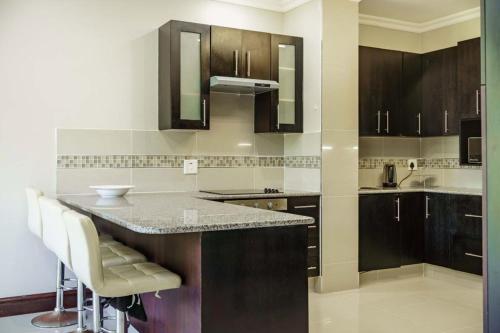 a kitchen with brown cabinets and a counter top at The Pearl Ballito in Ballito