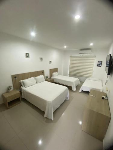 a hotel room with two beds and a television at Hotel River City in Montería
