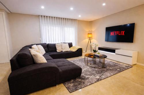 a living room with a couch and a tv at Modern Villa near Lisbon & Beaches with Heated Pool in Fernao Ferro