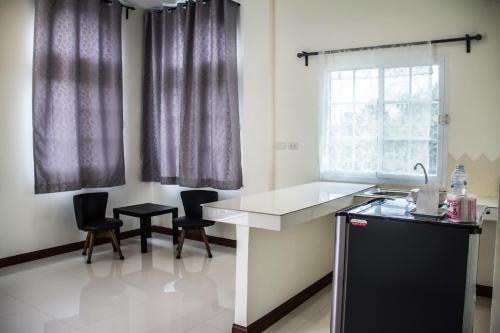 a kitchen with a counter and two chairs and a sink at Plern Pitch Residence in Pak Chong
