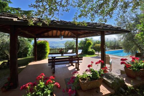 a wooden pergola with a bench and flowers at Casa Citille - Happy Rentals in Greve in Chianti