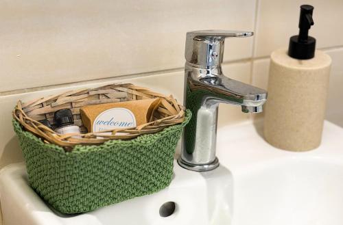 a bathroom sink with a faucet and a basket on it at Irene Studios in Arillas