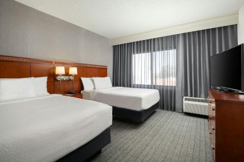 a hotel room with two beds and a flat screen tv at Courtyard by Marriott Albuquerque Airport in Albuquerque
