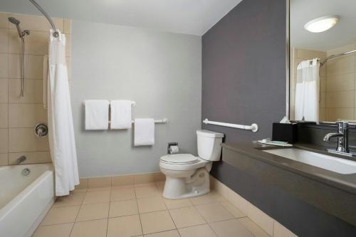 a bathroom with a toilet and a sink and a tub at Courtyard by Marriott Albuquerque Airport in Albuquerque