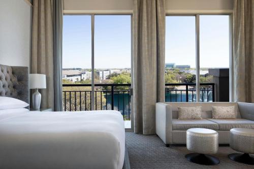a hotel room with a bed and a couch and windows at Dallas/Plano Marriott at Legacy Town Center in Plano