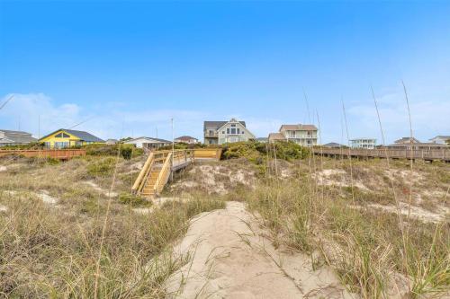a beach with houses and a wooden stairway in the sand at Azohva by Oak Island Accommodations in Caswell Beach