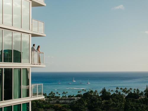 two people on the balcony of a building looking at the ocean at The Ritz-Carlton Residences, Waikiki Beach Hotel in Honolulu