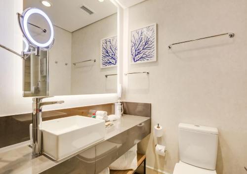 a white bathroom with a sink and a mirror at Radisson Pinheiros in São Paulo