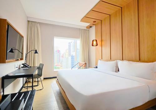 a hotel room with a large white bed and a desk at Radisson Pinheiros in São Paulo