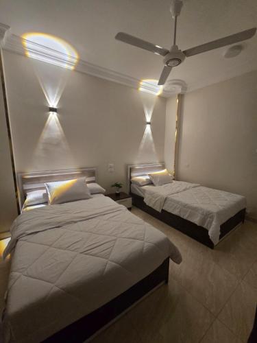 a bedroom with two beds and a ceiling fan at النزهه in Quseir