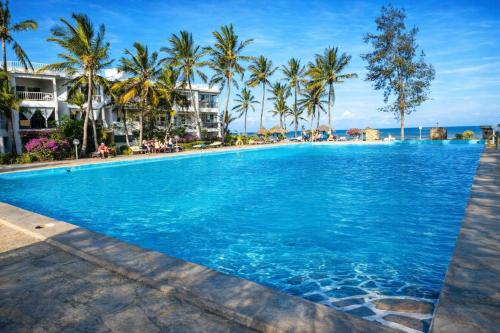 a swimming pool at a resort with palm trees at Crystal Apartments in Malindi