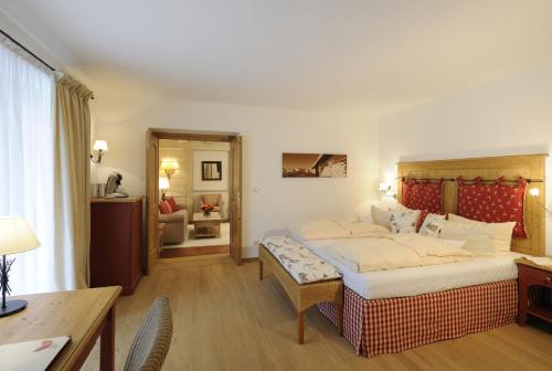 a hotel room with a large bed and a desk at Staudacherhof in Garmisch-Partenkirchen I Blick aufs Zugspitzmassiv I einzigartige Bayurvida Küche in Garmisch-Partenkirchen