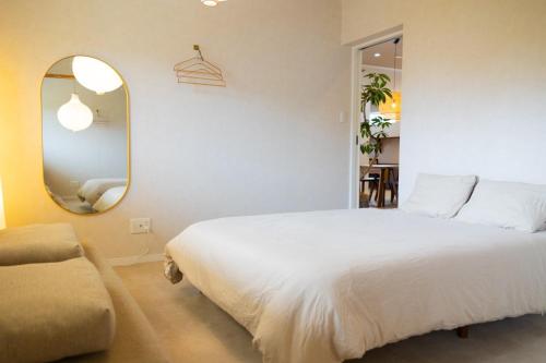 a bedroom with a large white bed and a mirror at YMA House in Nago