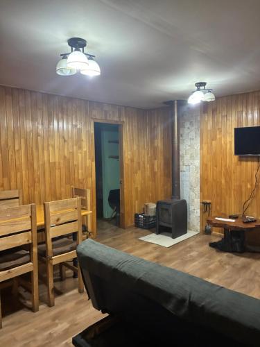 a living room with a couch and a television at Cabañas rio fuy Tinaja in Puyehue