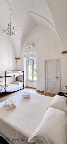 a large white room with two beds and a chandelier at Domus Avi - Bed and Breakfast in Taviano