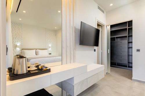 a white bedroom with a bed and a tv at FOGE luxury villa Agios Onoufrios in Chania