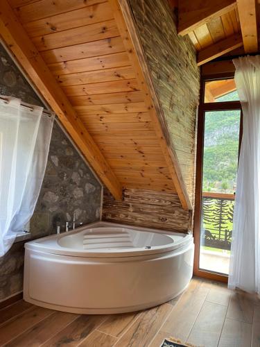 a large white tub in a room with a wooden ceiling at Golden Villa in Theth