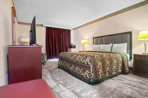 a hotel room with a bed and a flat screen tv at Airport Inn Memphis Near Graceland By Hotel O in Memphis