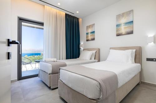 two beds in a hotel room with a balcony at FOGE luxury villa Agios Onoufrios in Chania
