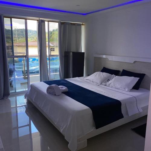 a bedroom with a large bed and a large window at Hotel Pacífico Azul in Bahía Solano