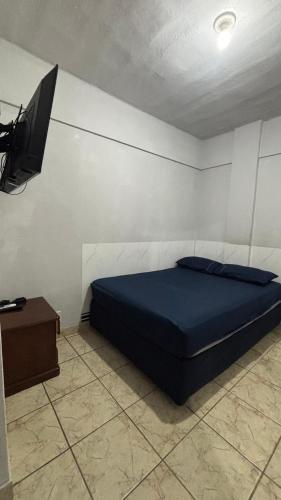 a bedroom with a blue bed and a television at Ótimo Quarto e Sala mobiliado em itapoa. in Vila Velha