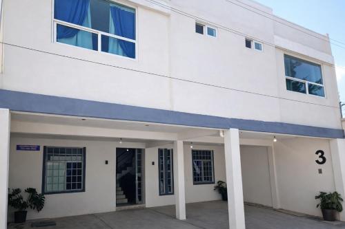 a white building with a blue stripe on it at Hotel Boutique Otomi cerca de Tolantongo in Cardonal