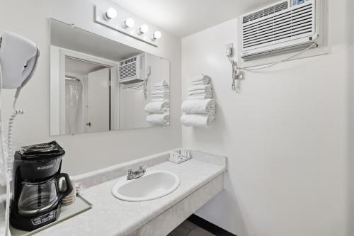 a white bathroom with a sink and a mirror at Canada's Best Value Desert Inn & Suites in Cache Creek