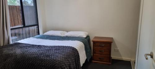 a bedroom with a bed and a dresser and a window at Ground level unit with private courtyard in Melton