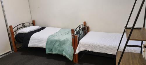 two twin beds in a room with white walls at Ground level unit with private courtyard in Melton