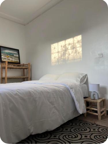 a white bedroom with a bed and a window at White House TAMRAGHT in Agadir