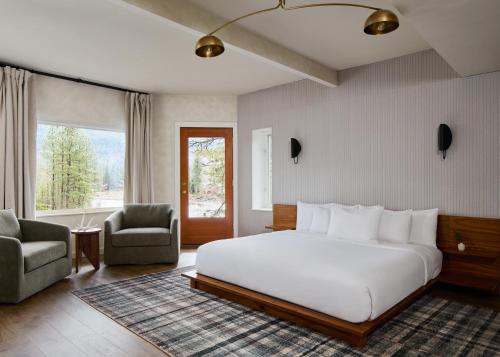 a bedroom with a large white bed and two chairs at All Seasons River Inn in Leavenworth