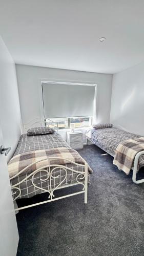 zwei Betten in einem Zimmer mit großem Fenster in der Unterkunft Bronte Snug in Bronte