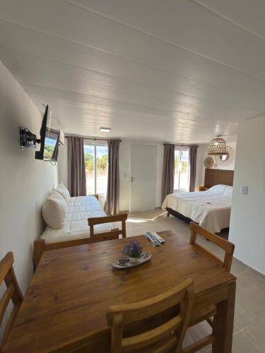 a room with a wooden table and a bedroom at Cabañas boutique la soñada BIS in Fiambalá