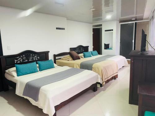 a bedroom with two beds with blue pillows at Hotel Colonial Betulia D in Tunja