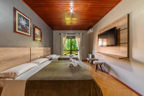 a bedroom with a large bed and a flat screen tv at Pousada Drehmer Haus in Gramado