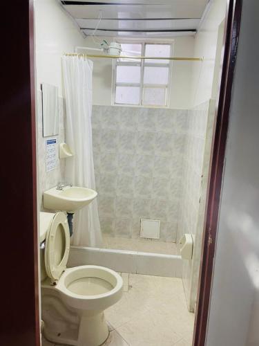 a bathroom with a toilet and a sink and a shower at Hotel Colonial El Bosque A in Tunja